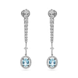 Pendientes de novia de oro blanco con diamantes y aguamarina oval rodeada de halo de diamantes.