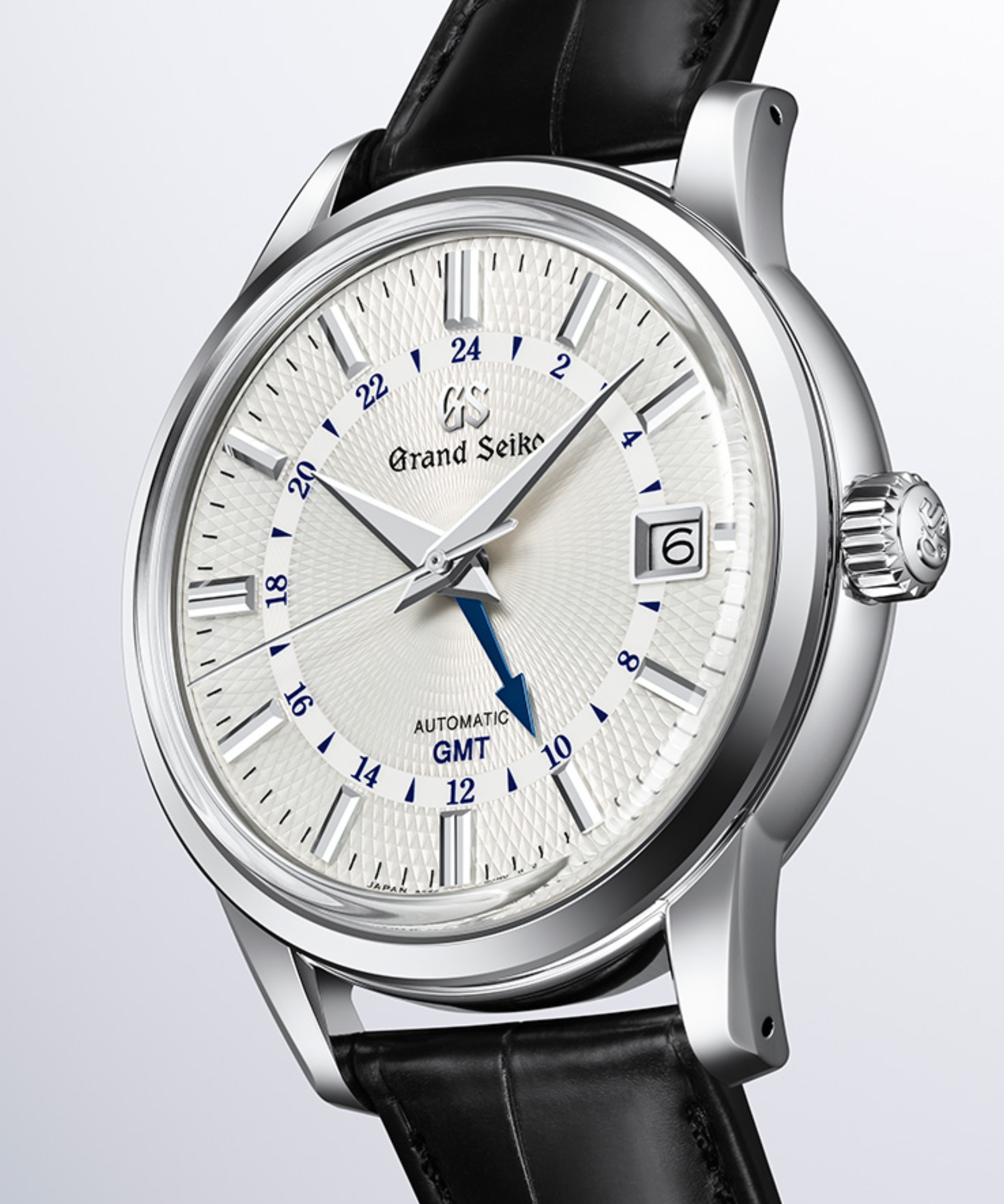 Esfera del reloj Grand Seiko SBGM255 Snowdrop con esfera blanca texturizada, aguja GMT azul y correa de piel.